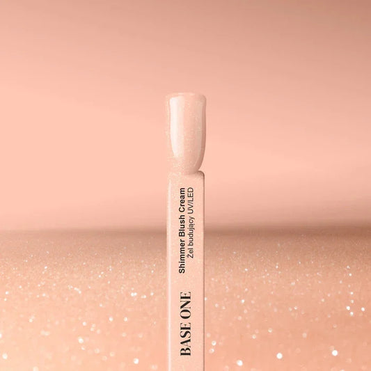 Cured nail tip displaying the warm beige Base One Shimmer Blush Cream builder gel (15g), featuring subtle, embedded shimmering particles.