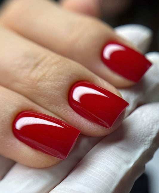 Glossy classic red gel manicure on short square-shaped nails.