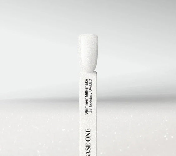 Swatch of Base One Shimmer Milkshake UV/LED builder gel, featuring a semi-transparent milky white finish with fine silver glitter particles on a nail tip.
