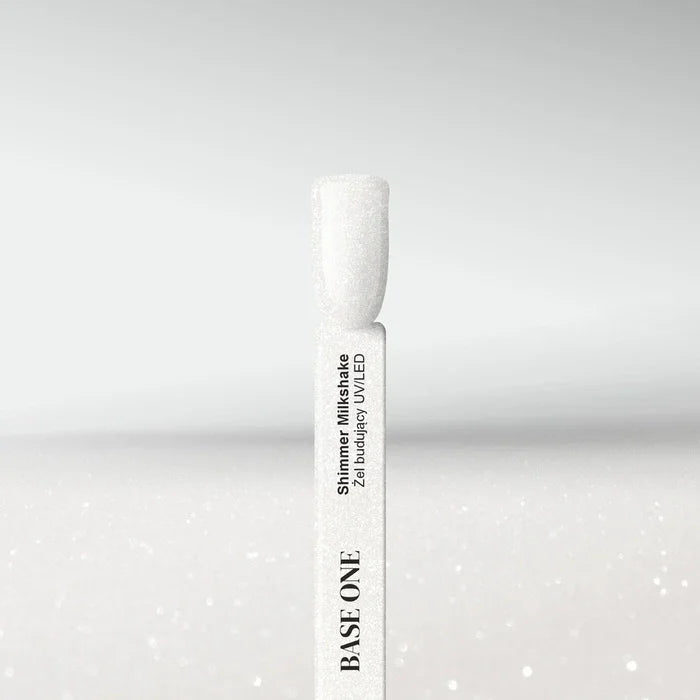 Swatch of Base One Shimmer Milkshake UV/LED builder gel, featuring a semi-transparent milky white finish with fine silver glitter particles on a nail tip.