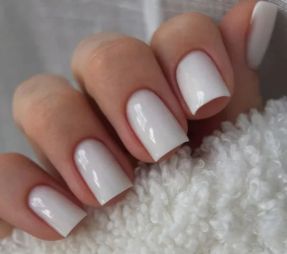 Woman's hand displaying nails finished with Base One Milkshake UV builder gel (15g), showing the natural, opaque milky white manicure.