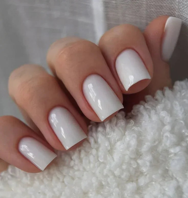 Woman's hand displaying nails finished with Base One Milkshake UV builder gel (15g), showing the natural, opaque milky white manicure.