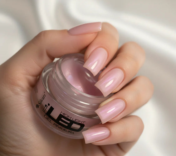 Hand with a full coverage manicure using the High Light LED Aura Pink Builder Gel, holding the product jar to showcase the final pink pearl effect.