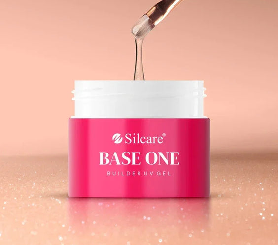 Nail brush holding a small bead of the medium-thick, shimmery Base One Blush Cream builder gel, showing controlled viscosity and embedded glitter.