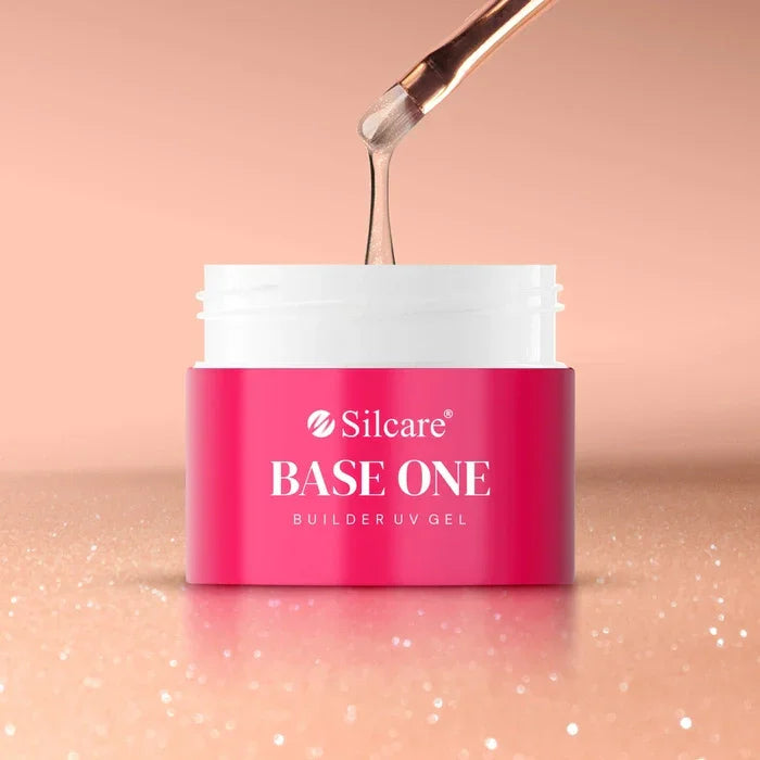 Nail brush holding a small bead of the medium-thick, shimmery Base One Blush Cream builder gel, showing controlled viscosity and embedded glitter.