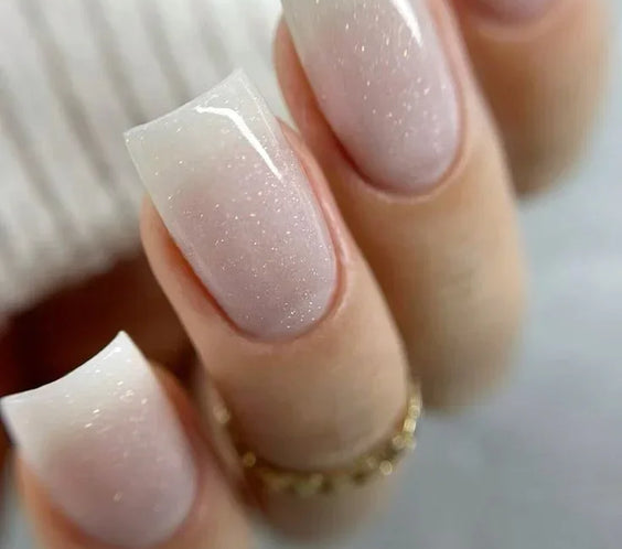 A professional manicure featuring square-shaped nails using Silcare Base One Builder Gel in Shimmer Milkshake, showing the milky white glitter effect.
