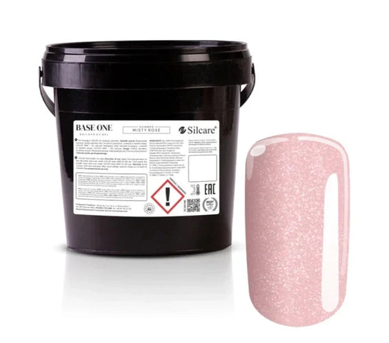 Shimmer Misty Rose Silcare Base One Builder Gel bulk salon bucket packaging with product label, shown next to a glossy nail swatch displaying soft rosy pink colour with fine shimmer, isolated on a clean light background for professional nail supply presentation.