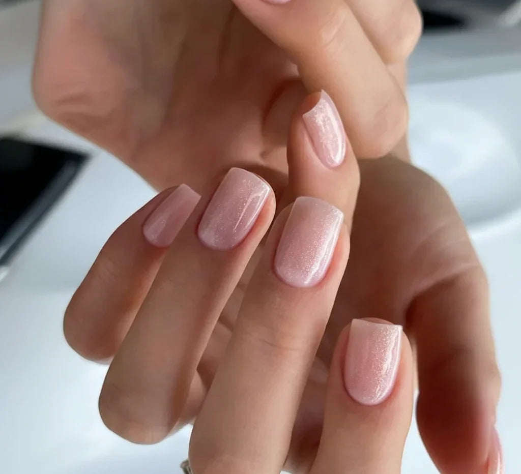 Close-up of short square manicured nails featuring shimmering pale pink Base One Builder Gel in Shimmer Vanillia Rose by Silcare.