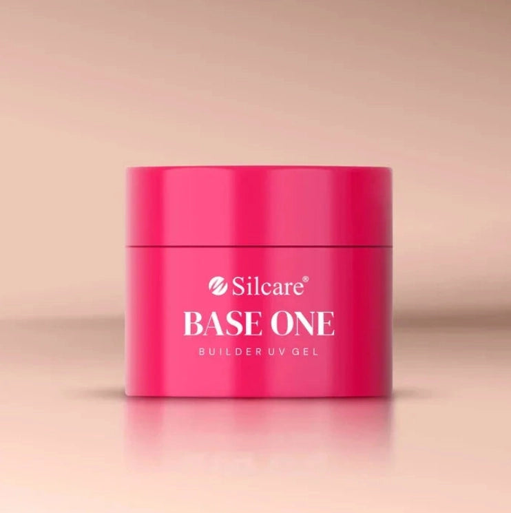 Front view of the Silcare Base One Builder UV Gel jar in bright pink packaging with the Silcare logo and "BASE ONE Builder UV Gel" printed on the container. The closed gel jar is photographed against a soft beige background, showcasing the professional nail builder gel packaging used for nail extensions, overlays, and salon manicures.