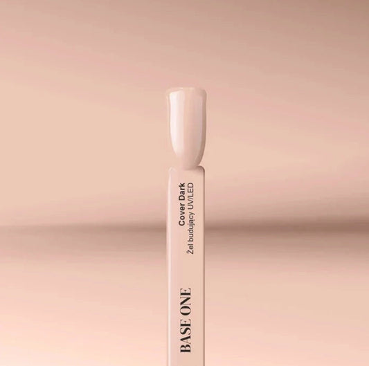 Close-up of the Silcare Base One Cover Dark builder UV/LED gel colour swatch stick featuring a glossy nude beige shade. The swatch displays the product name "Cover Dark" on a white sample stick against a soft beige background, illustrating the natural camouflage colour for nail extensions, overlays, nail bed enhancement, and professional salon manicures.