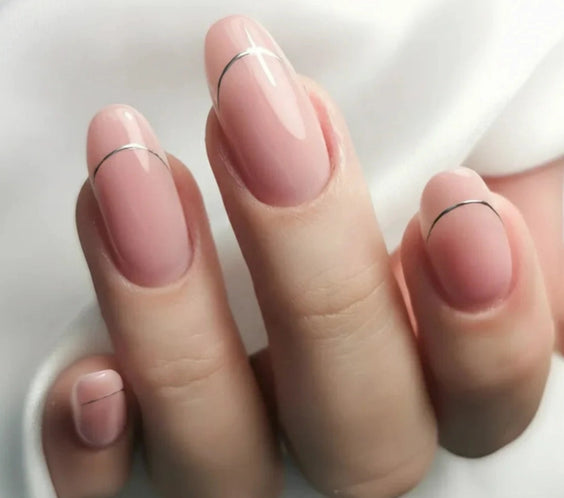 Close-up of a manicure created using Silcare Base One Cover Dark builder gel, featuring glossy natural pink oval nails with delicate thin black French tip accents. The elegant nude camouflage manicure is shown on a hand against a soft white background, highlighting the builder gel's natural coverage and salon-quality finish for nail extensions and overlays.