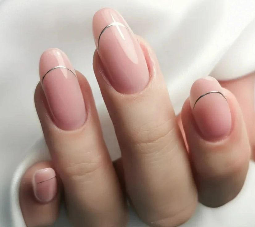 Close-up of a manicure created using Silcare Base One Cover Dark builder gel, featuring glossy natural pink oval nails with delicate thin black French tip accents. The elegant nude camouflage manicure is shown on a hand against a soft white background, highlighting the builder gel's natural coverage and salon-quality finish for nail extensions and overlays.