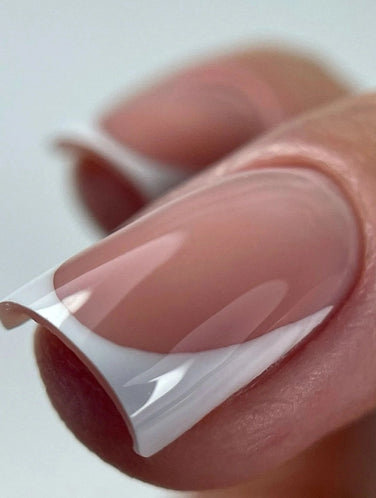 Extreme close-up of a French manicure created with Silcare Base One French White Marble builder gel, featuring a crisp white French tip and a glossy natural pink nail bed. The elegant nail enhancement showcases smooth self-levelling application, high opacity white coverage, and professional salon-quality results for French nails, overlays, and nail extensions.