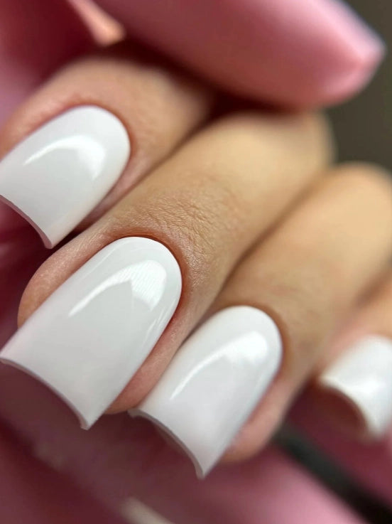 Close-up of a glossy white square-shaped manicure created with Silcare Base One French White Marble builder gel. The nails feature a smooth, opaque white finish with high shine, showcasing the builder gel's professional coverage, self-levelling formula, and salon-quality results for French manicures, nail extensions, overlays, and modern white nail designs.