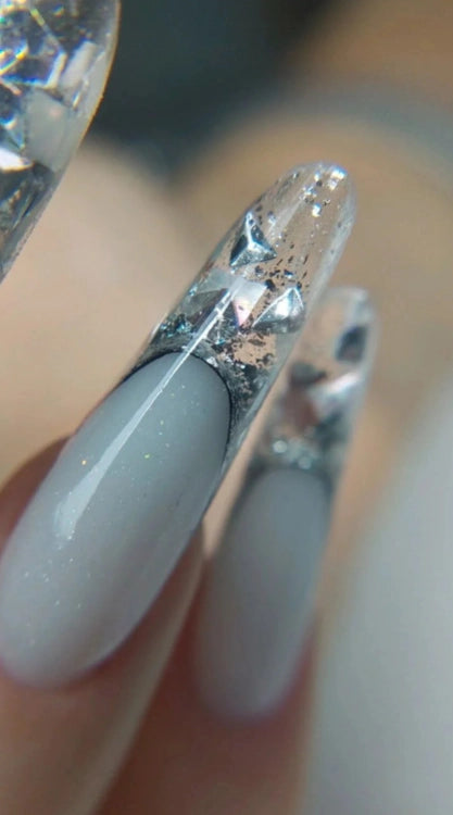 Close-up of almond-shaped nails created with Silcare High Light LED Blue clear UV/LED builder gel, featuring a crystal-clear encapsulated nail design with silver glitter and faceted crystal accents over a soft milky base. Professional self-levelling clear builder gel for encapsulated nail art, extensions and salon-quality manicures – Silcare Australia.