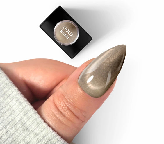 A long almond-shaped nail featuring Silcare maniMORE Gold Rush magnetic gel polish with a velvet cat-eye effect, shown next to the product bottle.